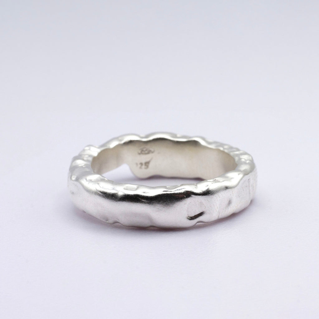Silver ring with a textured design on a light gray background