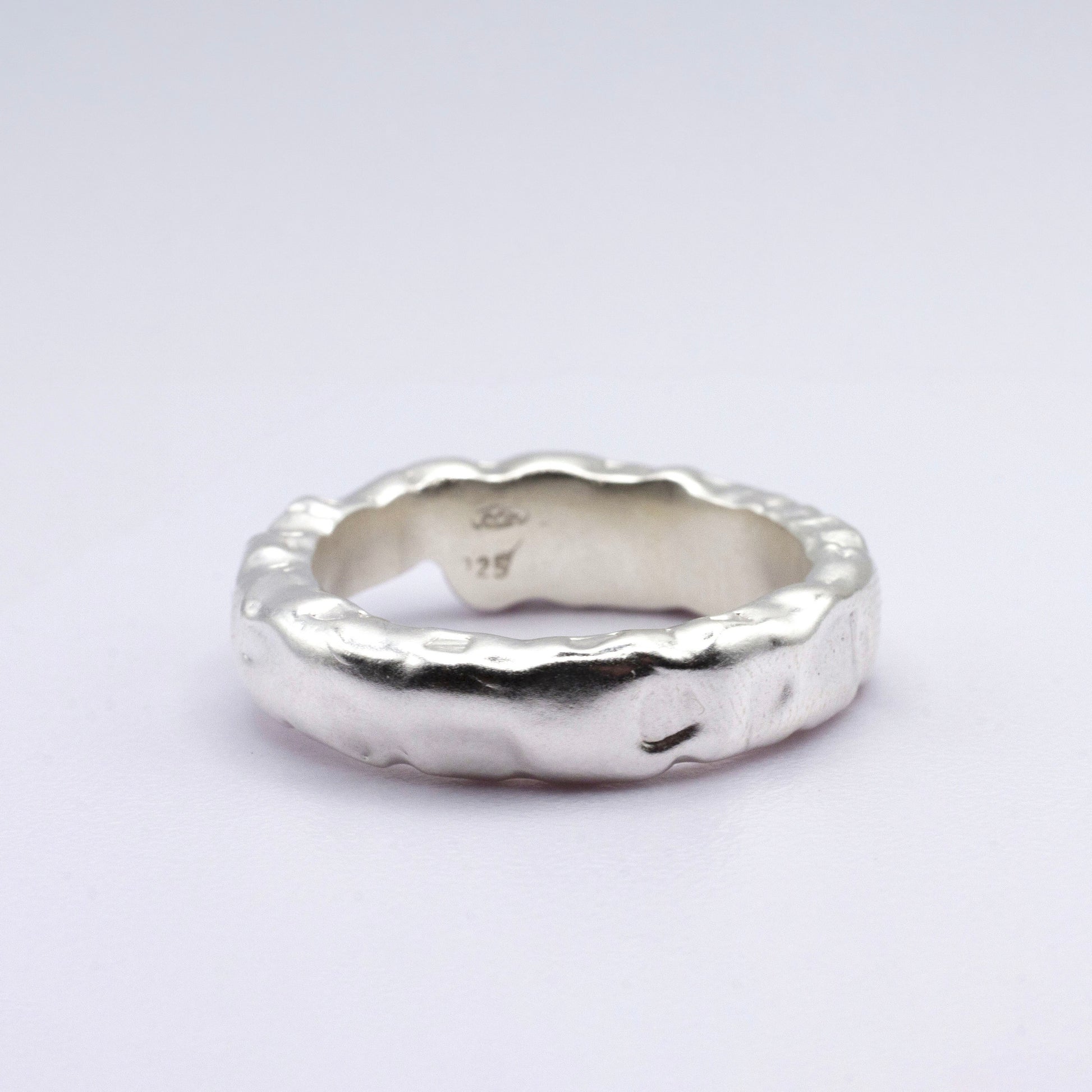 Silver ring with a textured design on a light gray background