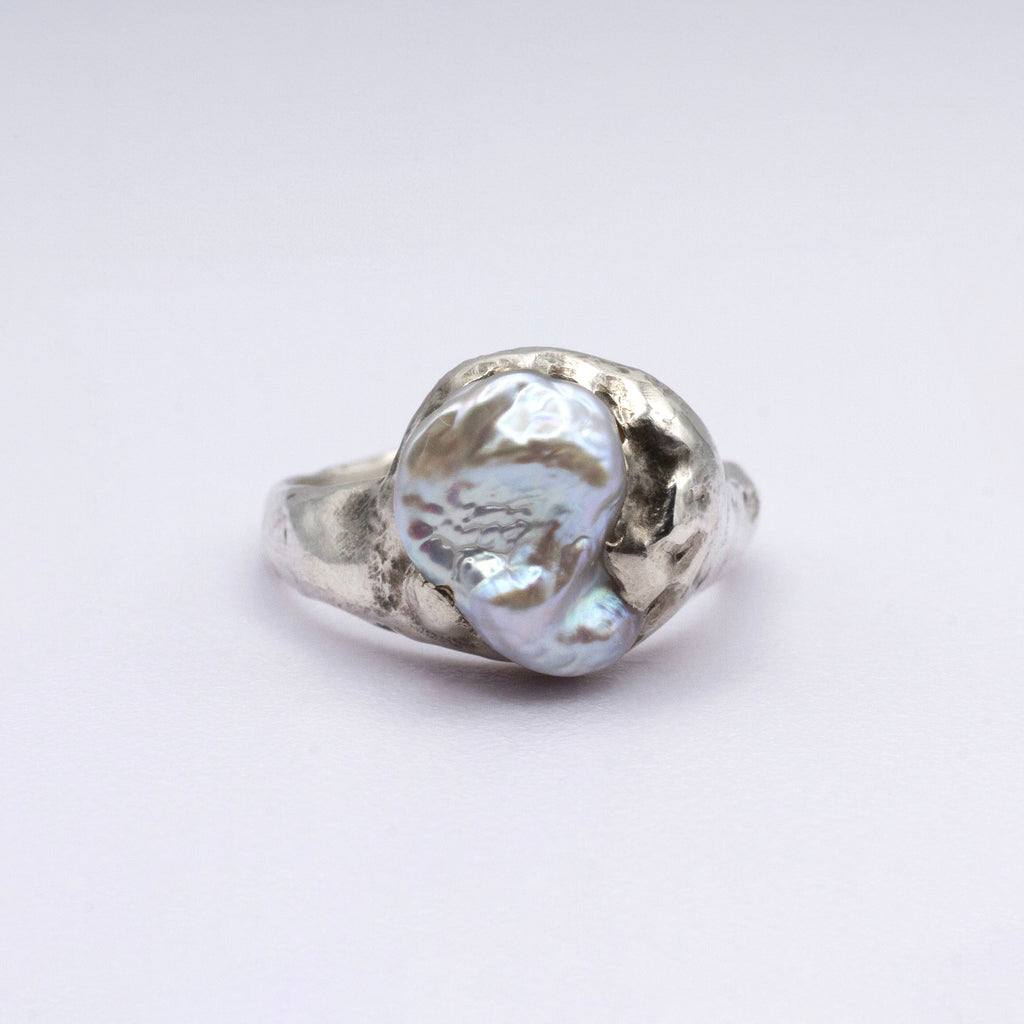 Silver ring with a large pearl on a white background