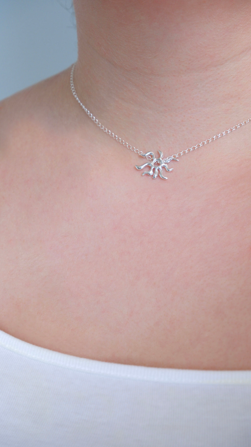 Silver necklace with a star-shaped pendant on a person wearing a white top.
