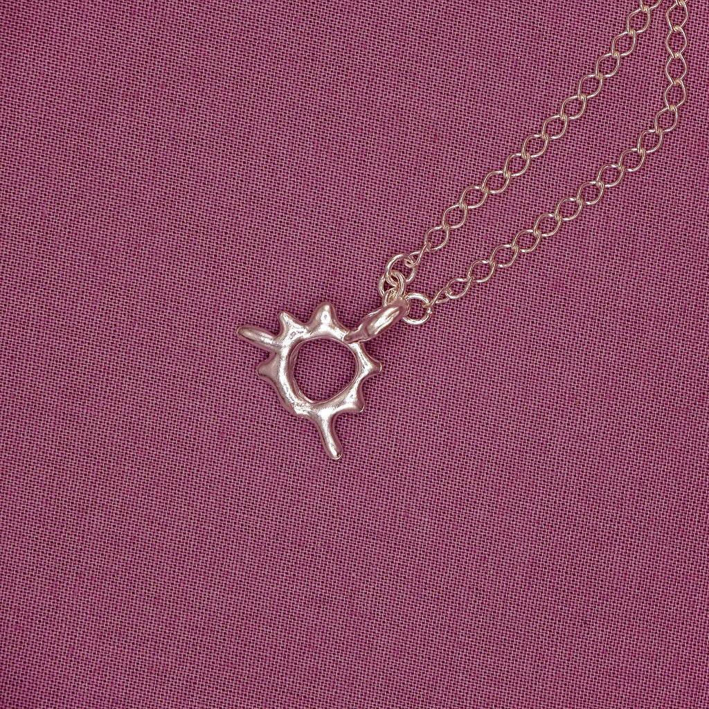 Silver bracelet with a unique pendant on a purple fabric background