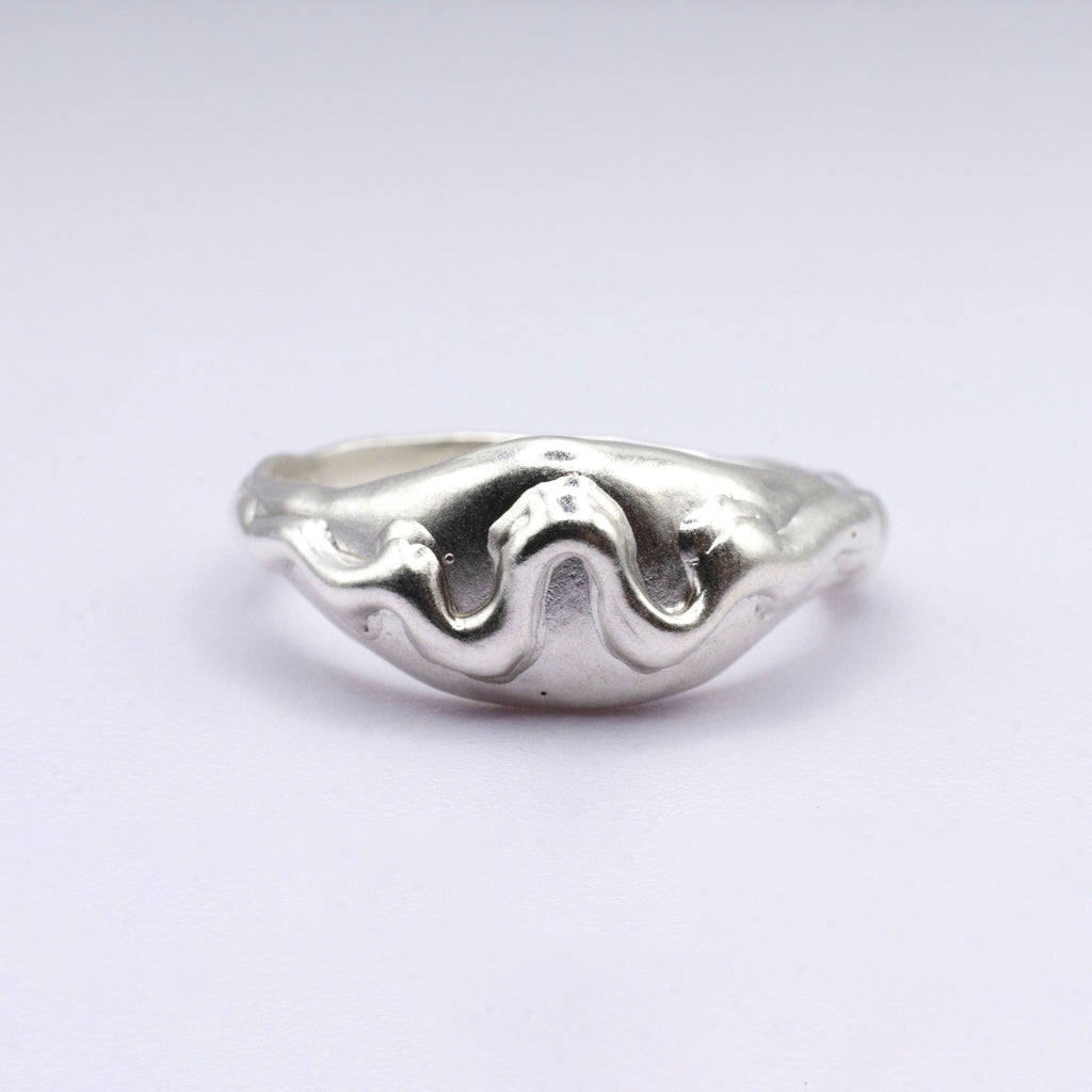 Silver ring with wavy design on a light gray background