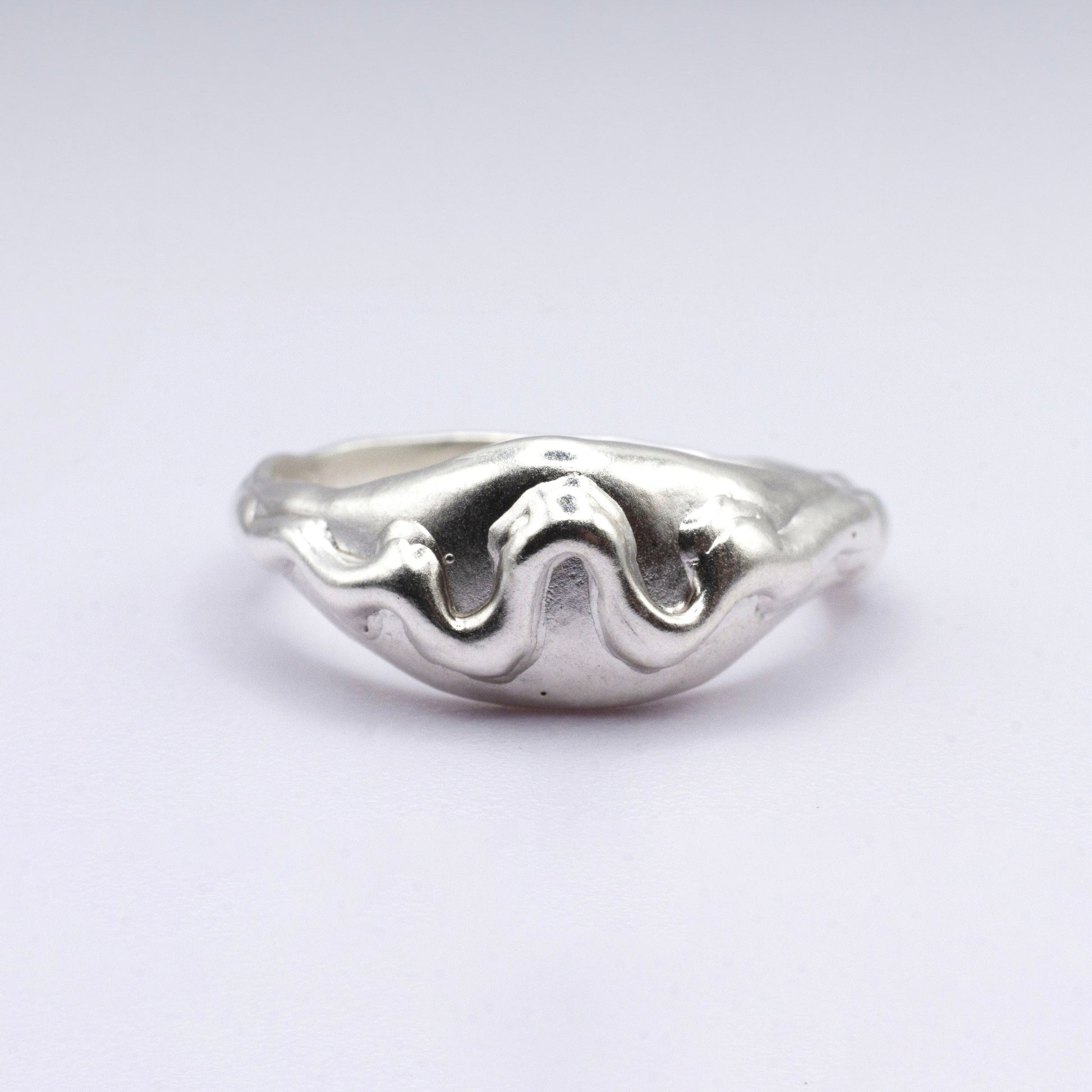 Silver ring with wavy design on a light gray background