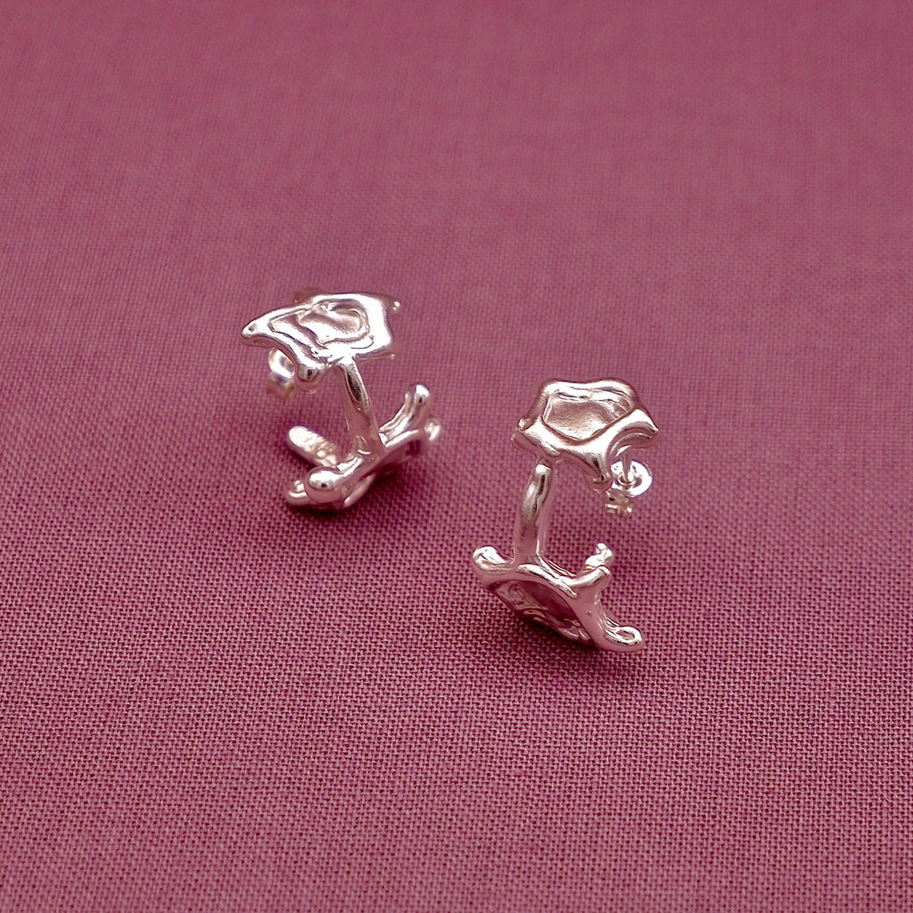 Pair of silver earrings on a pink fabric background