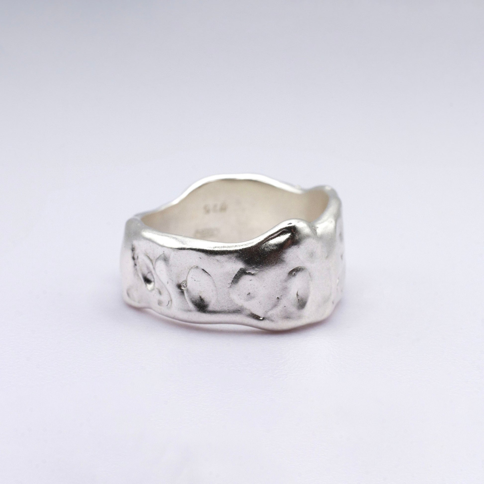 Silver ring with a textured design on a light gray background