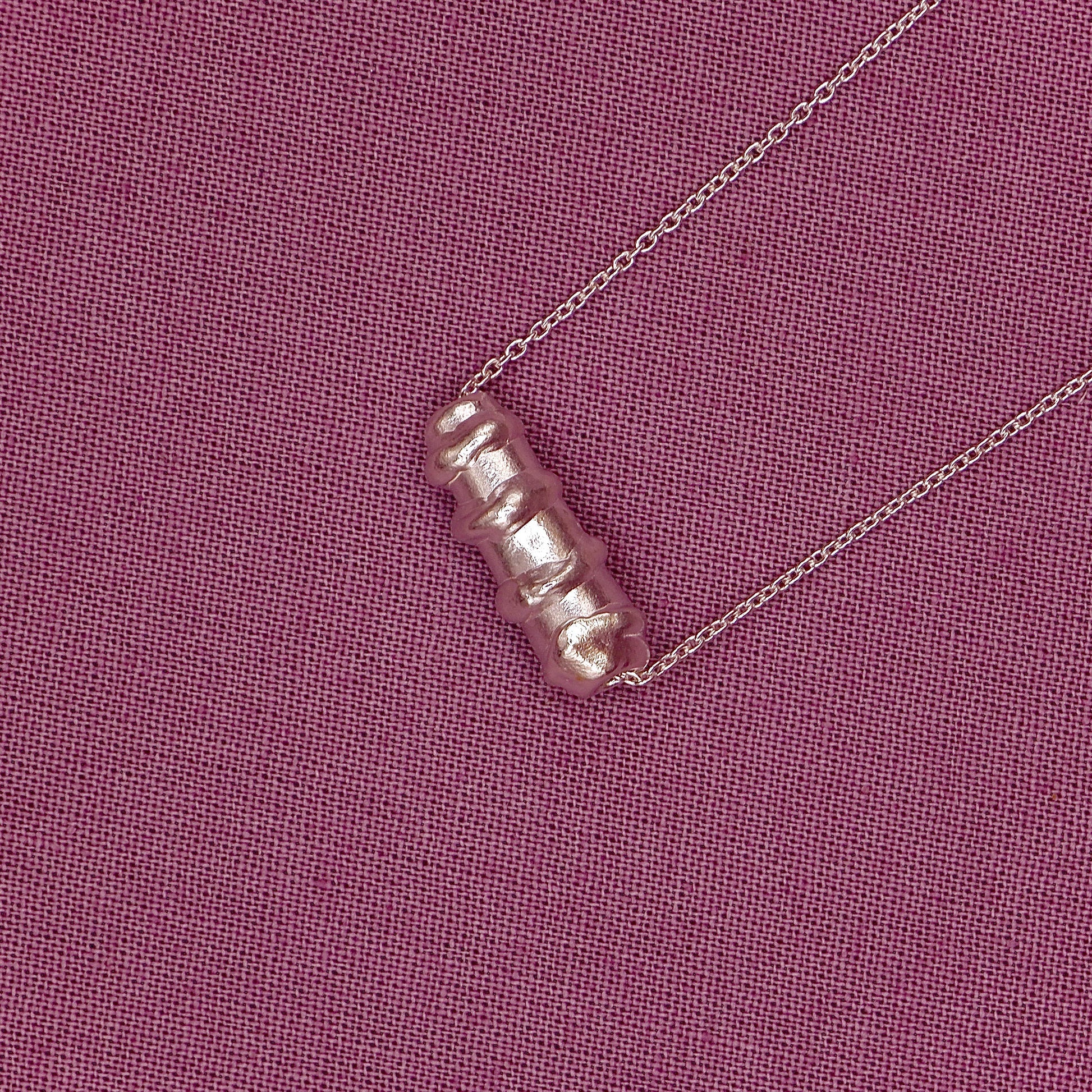 bracelet with a unique pendant on a pink textured background