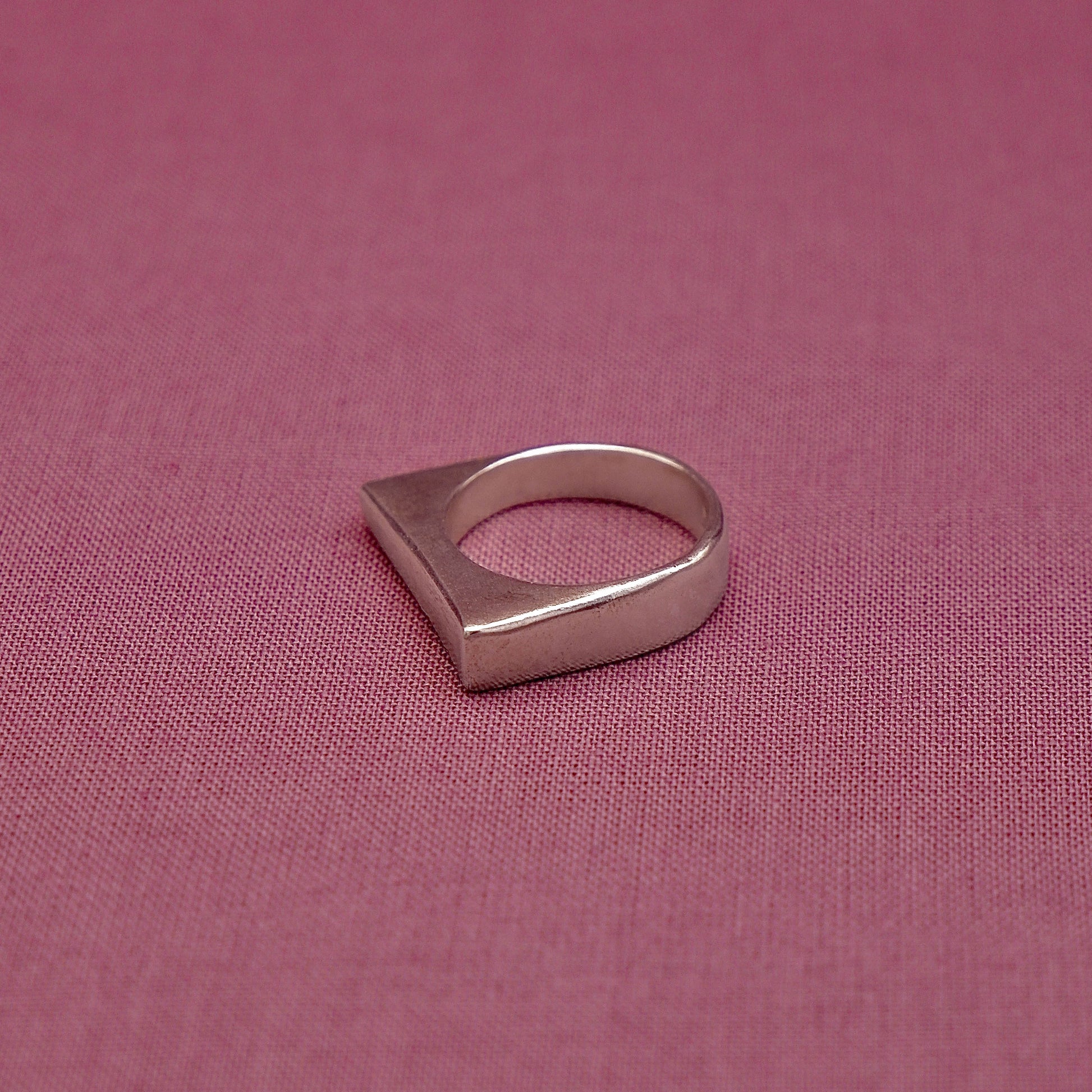 Silver ring with a unique design on a pink fabric background