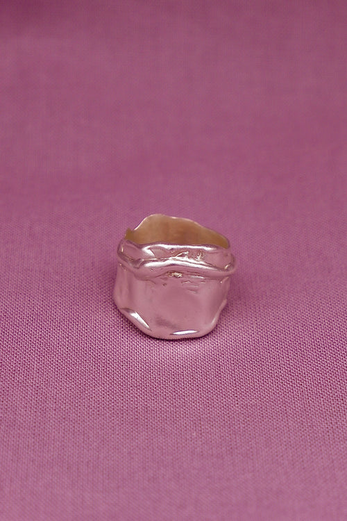 Silver ring with a gold band on a pink fabric background