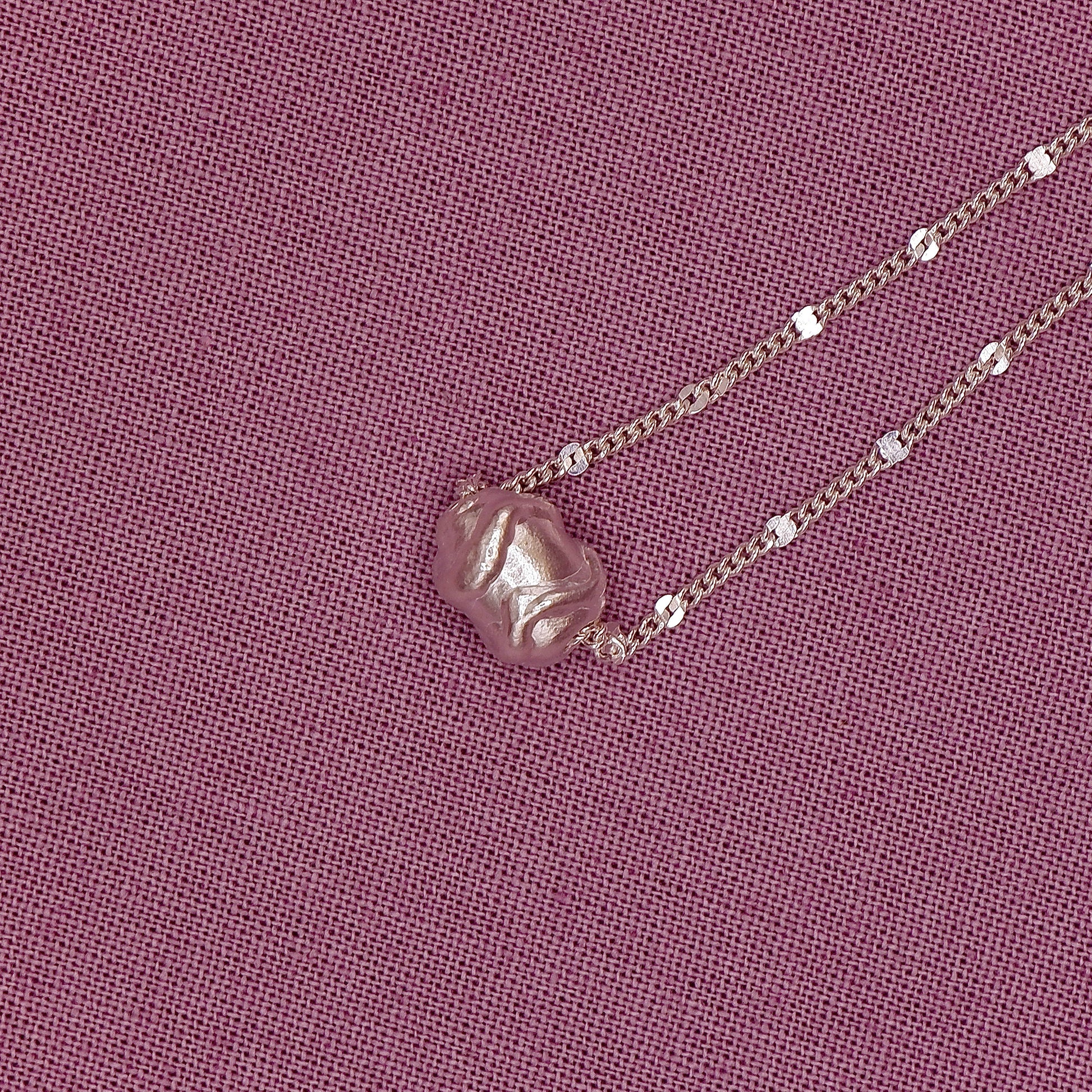 Necklace with a pendant on a pink fabric background
