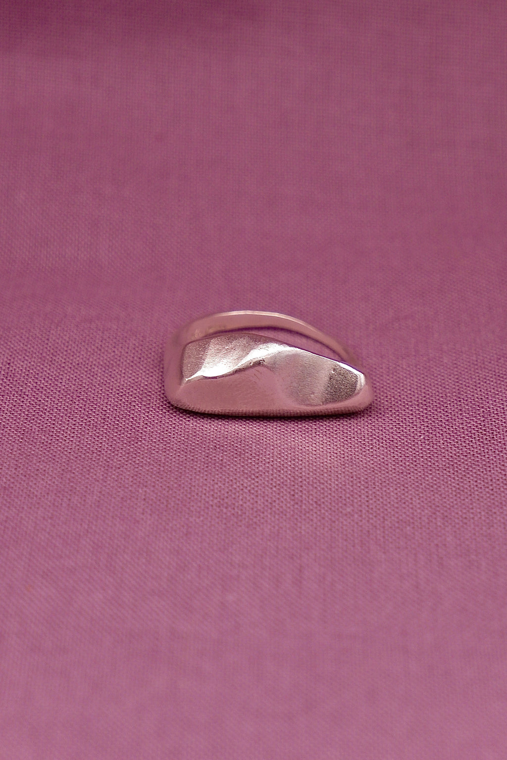 Silver ring on a pink fabric background