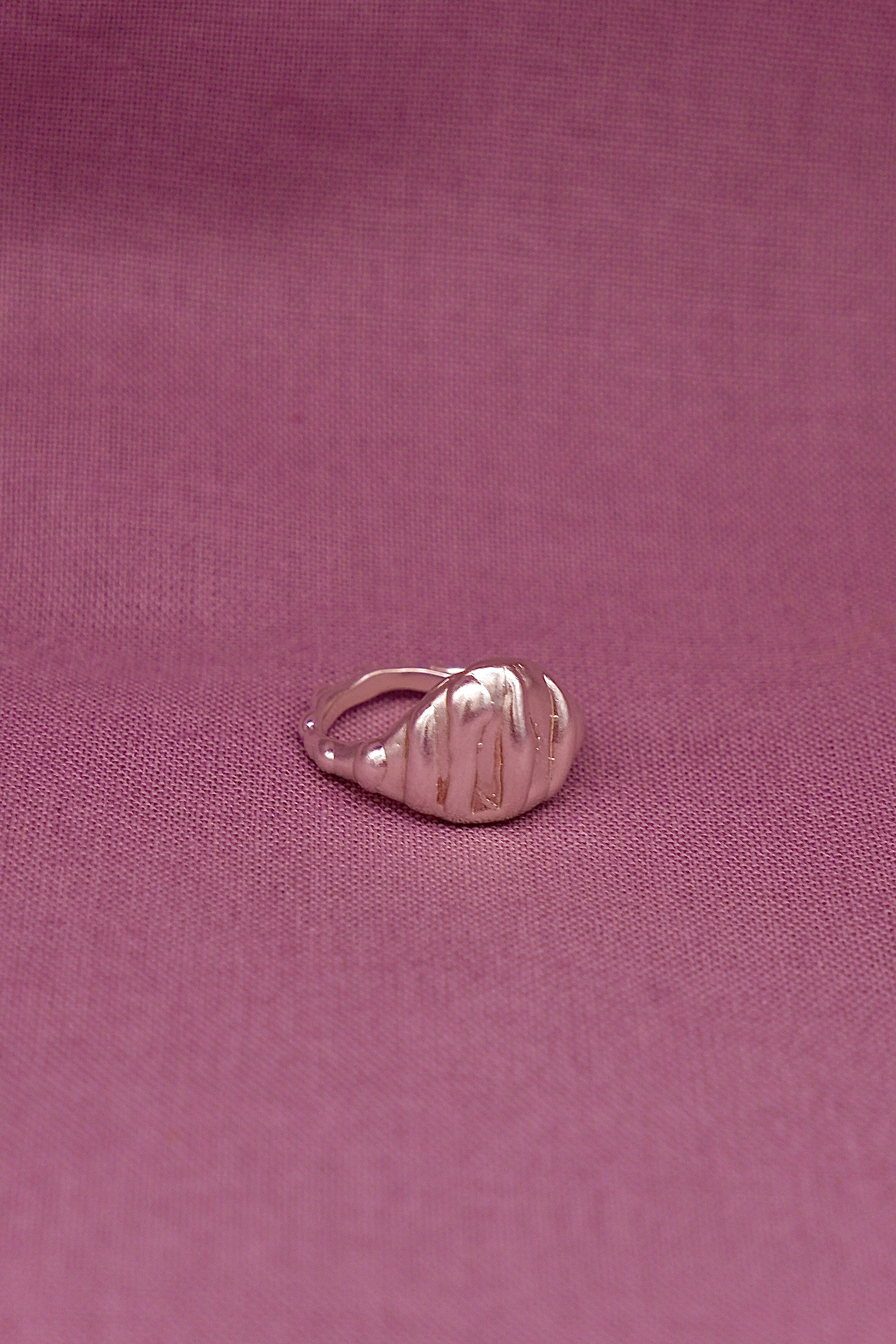 Silver ring on a pink fabric background