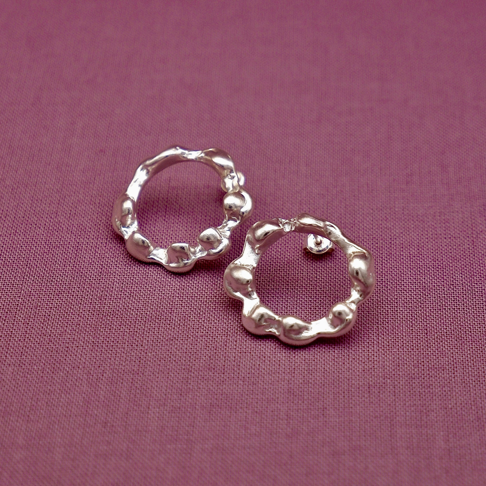 Silver hoop earrings on a purple fabric background
